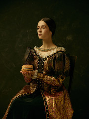 Portrait of a girl wearing a princess or countess dress over dark studio. portrait with burger
