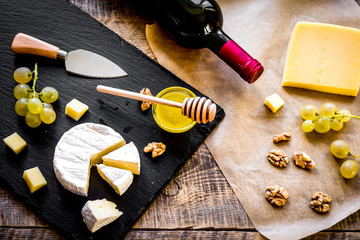bottle of red wine, appetizers and corkscrew on wooden backgroun