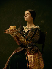 Portrait of a girl wearing a princess or countess dress over dark studio. portrait with burger
