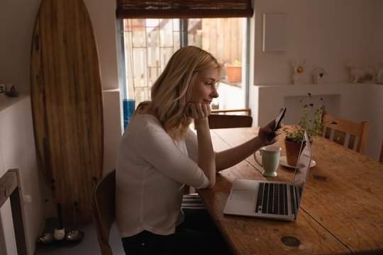 Side view of woman using smartphone at home