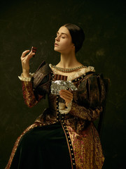 Fototapeta premium Portrait of a girl wearing a princess or countess dress over dark studio. portrait with sweet chocolate bar over dark studio