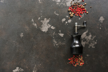 Peppercorns and pepper mill on a dark rustic background.Top view, flat lay,space for text.
