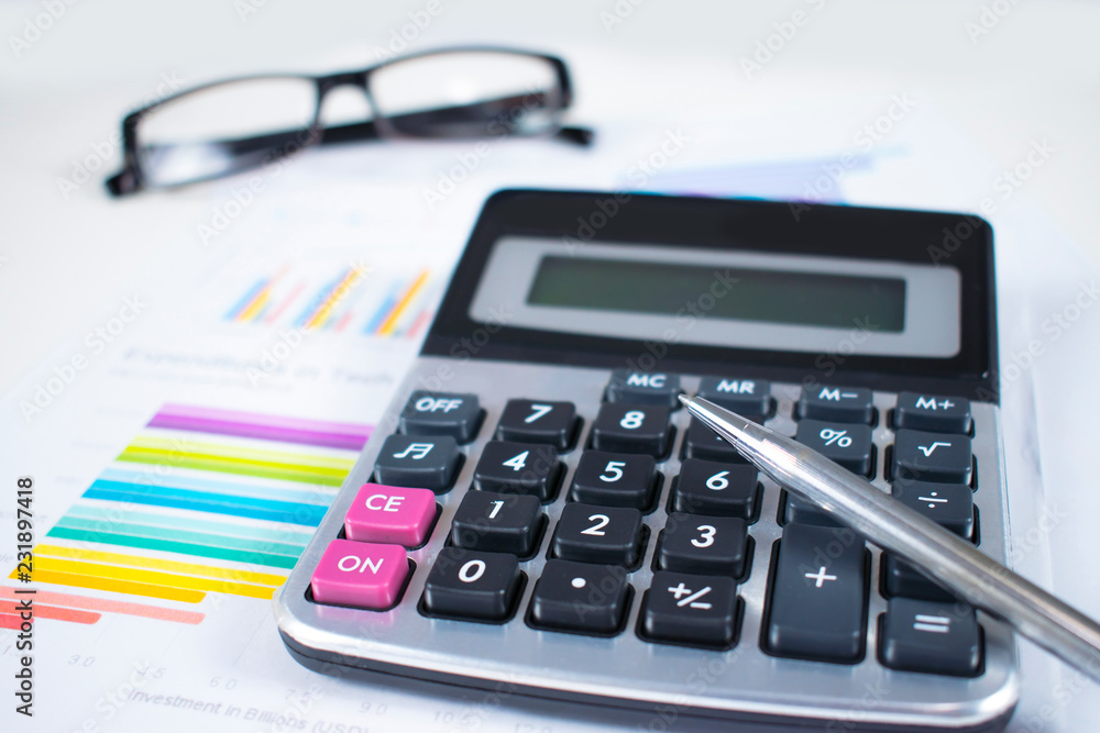 Poster on a modern white desk there is a pen placed on a business calculator and graph. working desk table 