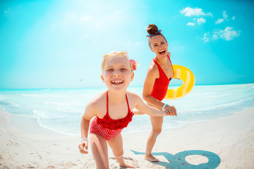 mother and daughter with yellow inflatable lifebuoy on beach