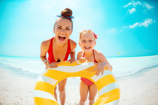 happy mother and daughter holding yellow inflatable lifebuoy