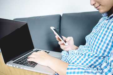 People are using his smartphone for online banking and sitting on a sofa with a computer.