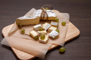 camembert cheese and grapes on the wood board	
