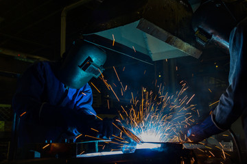 Industrial worker is welding in factory