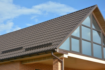 Fototapeta premium Modern house attic metal tile roof with panoramic glass wall window and roof gutter.