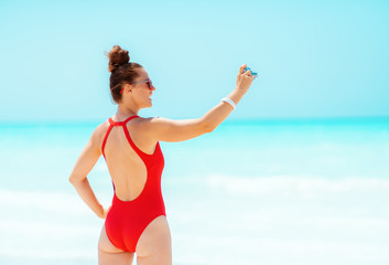 young woman taking photos with retro photo camera on seacoast