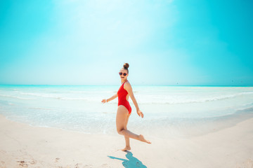 Fototapeta na wymiar smiling young woman in red swimwear on beach having fun time