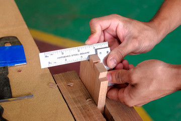 Skilled joiner working in carpentry. Amateur woodworker making dovetail join for wooden drawer in carpenters workshop