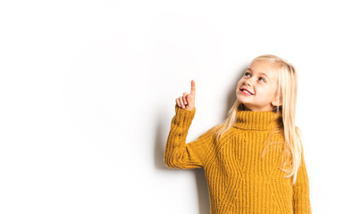 A Cute girl 5 year old posing in studio pointing