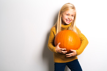 A Cute girl 5 year old posing in studio with pumpkin