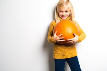 A Cute girl 5 year old posing in studio with pumpkin