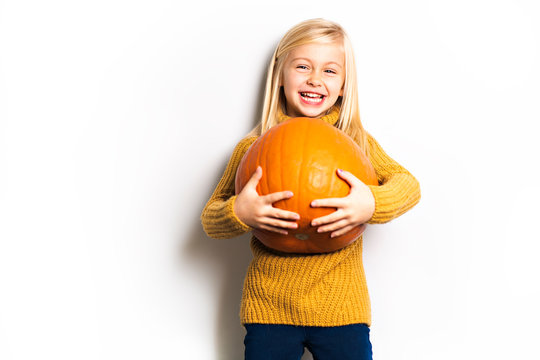 A Cute girl 5 year old posing in studio with pumpkin