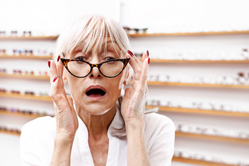 Starsza kobieta przymierza oprawki okularowe. 