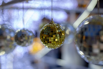 Gold christmas disco ball on blurred festive background in time for new year holiday