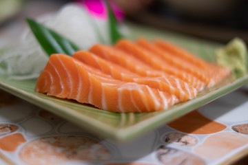 Close up of Salmon raw sashimi on green Japanese traditional dish on the table.