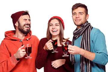 Smiling european men and women during party photoshoot. The guys posing as friends at studio fest with wineglasses with hot mulled wine on foreground.
