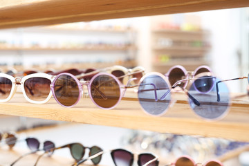 Okulary przeciwsłoneczne, modny dodatek do stylizacji. Półka z okularami przeciwsłonecznymi w sklepie odzieżowym.