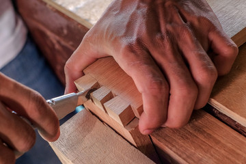 Skilled joiner working in carpentry. Amateur woodworker making dovetail join for wooden drawer in...