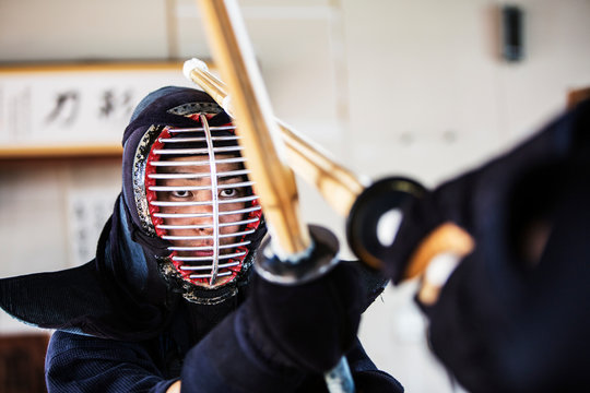 Close up of Japanese Kendo fighter wearing Kendo mask in combat pose.