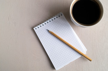 Top view of the notebook, a Cup of coffee on a bright table.