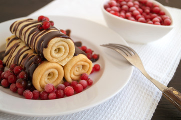 Homemade pancakes twisted with chocolate on a white plate.