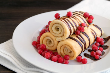 Homemade pancakes twisted with chocolate on a white plate.