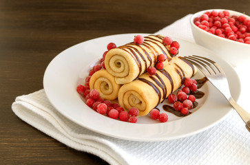 Homemade pancakes twisted with chocolate on a white plate.