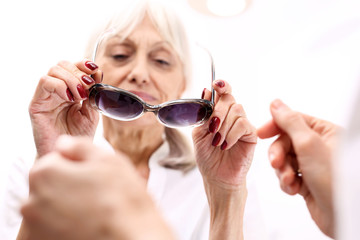 Ochrona oczu przed słońcem, okulary przeciwsłoneczne z filtrem.Starsza kobieta kupuje okulary...