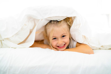 A Cheerful little girl in bed having fun