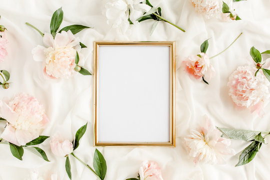 Gold frame decorated of beautiful beige peonies. Flat lay, top view. Valentine's background. Floral frame. Peony texture.