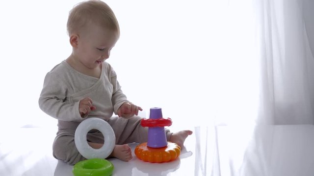 educational toys, happy baby boy is played with pyramid toy at home close-up