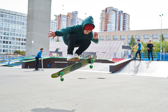 Full length portrait of modern teenager doing skateboard stunts in extreme park, copy space