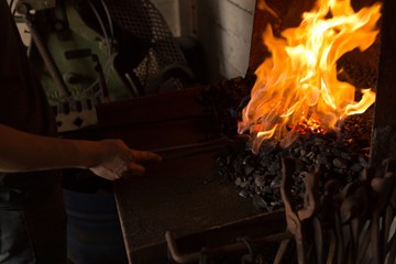 Female metalsmith heating horseshoe in fire