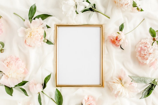 Gold frame decorated of beautiful beige peonies. Flat lay, top view. Valentine's background. Floral frame. Peony texture.