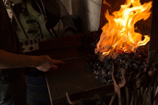 Female metalsmith heating horseshoe in fire