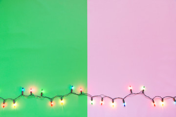 Christmas light bulbs were turned on or lid on string in colours; blue, yellow, red, pink, orange and green over pink & green background, holiday concept for Xmas or special occasion celebration