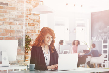 Smiling businesswoman using laptop while working in international company