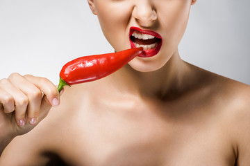 close up of young beautiful woman with red lips biting chili pepper