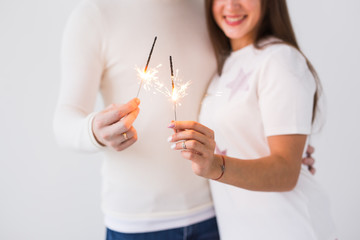 Romantic beautiful couple having date at Valentine's Day. Close up of man and woman holding champagne glasses and sparklers.