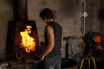 Female metalsmith heating horseshoe in fire