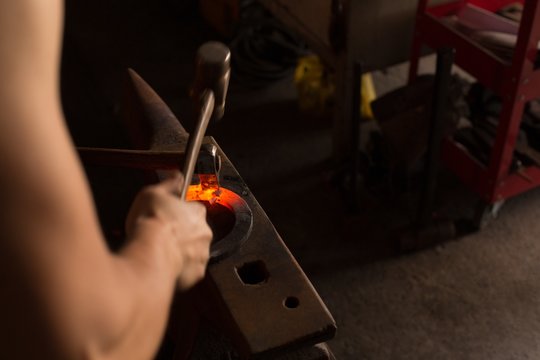 Female metalsmith molding horseshoe in factory