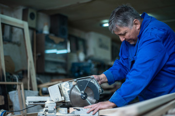 electric saw for sawing boards, the worker saws a wooden board in workshop
