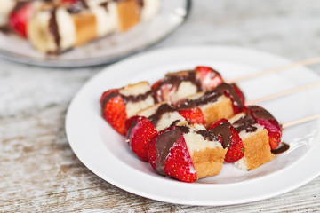 Fruit and cake skewers with melted chocolate