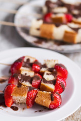 Fruit and cake skewers with melted chocolate
