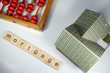 Mortgage word tiles with abacus and house miniature 