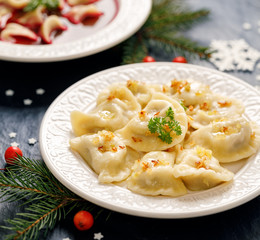 Christmas dumplings stuffed with  mushroom and cabbage on a white plate on a dark background. Vegetarian food, Traditional Christmas eve dish in Poland